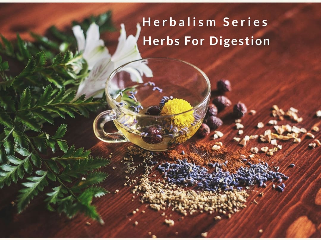 A wooden table with herbs and an herb cup.
