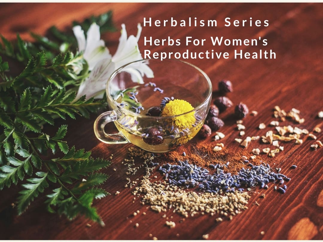 A wooden table topped with herbs and a glass.
